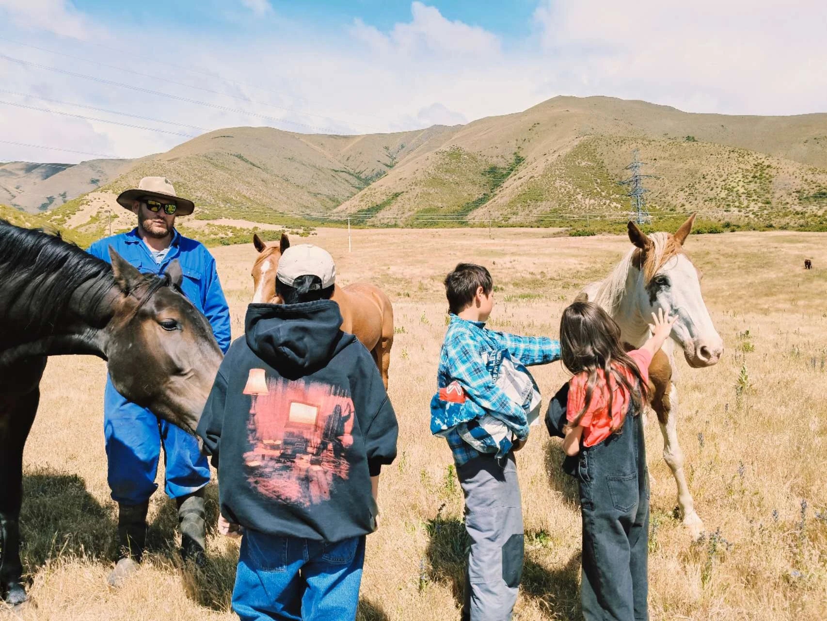 A family meeting horses in an open high-country landscape